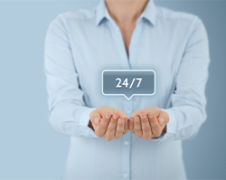 Woman in button up shirt holding her hands out with 24/7 on top